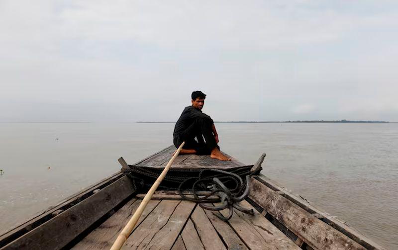 A man sits in a boat on the waters of the Brahmaputra river near the international border between India and Bangladesh in Dhubri district, in the northeastern state of Assam, India - REUTERSpix