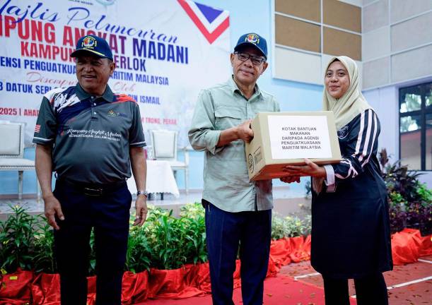 Menteri Dalam Negeri Datuk Seri Saifuddin Nasution Ismail menyampaikan kotak bantuan makanan kepada masyarakat setempat, Roshidah Taha pada Majlis Peluncuran Kampung Angkat MADANI Agensi Penguatkuasaan Maritim Malaysia Tahun 2025 di Dewan Perdana Mukim Trong hari ini. - Bernama