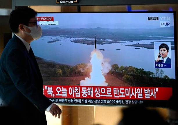 A man walks past a television screen showing a news broadcast with file footage of a North Korean missile test, at a train station in Seoul on October 31, 2024. North Korea on October 31 fired a “long-range ballistic missile”, South Korea’s military said, Pyongyang’s first weapons test since Seoul accused it of sending tens of thousands of soldiers to Russia. - JUNG YEON-JE / AFP