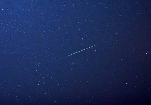 A falling star crosses the night sky over Halle / Saale, eastern Germany, during the peak in activity of the annual Perseids meteor shower on August 13, 2015. The Perseids meteor shower occurs every year when the Earth passes through the cloud of debris left by Comet Swift-Tuttle. AFP PHOTO / DPA / HENDRIK SCHMIDT