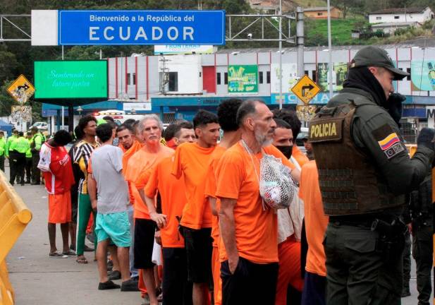 Inmates queue up before being deported to Colombia at the Rumichaca international bridge between Tulcan, Ecuador and Ipiales, Colombia on July 26, 2025. - AFP