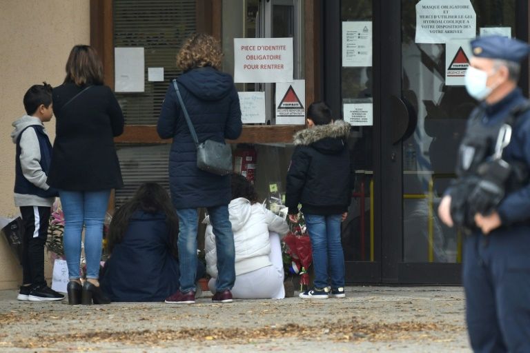 People place flowers at the doors of a Paris school where the beheaded teacher worked. — AFP