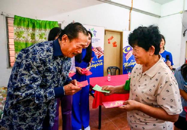 Tan presenting ang pow to PRR residents at the event. - ADAM AMIR HAMZAH/THESUN