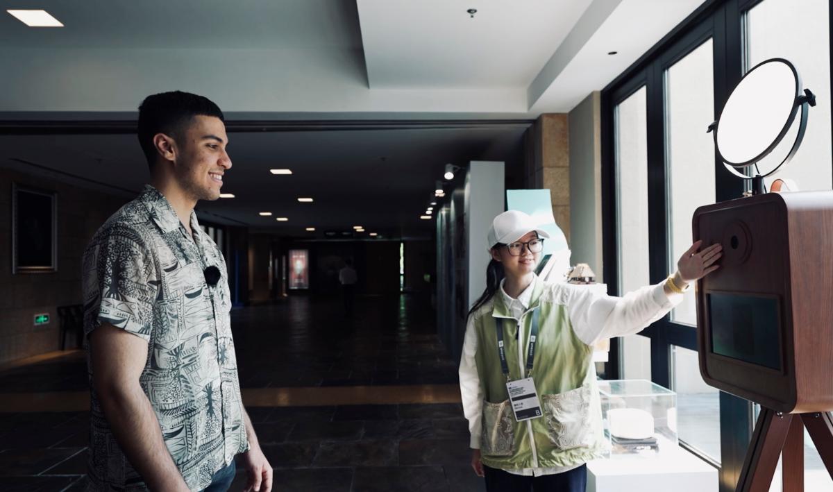Moroccan youth Aymene engaged with the “Liangzhu Ancestors AI Face Swap Generator” at Liangzhu Museum, using artificial intelligence to create a personal portrait infused with Liangzhu cultural elements.