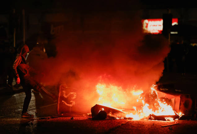A demonstrator kicks an object into a fire as riots continue in Ballymena, Northern Ireland, June 11, 2025. - REUTERSpix