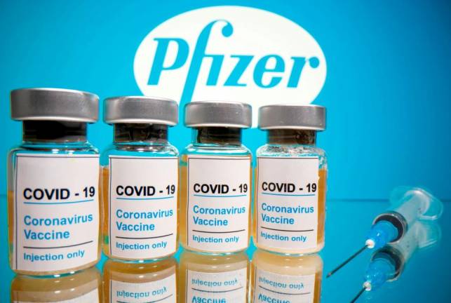 FILE PHOTO: Vials with a sticker reading, “COVID-19 / Coronavirus vaccine / Injection only” and a medical syringe are seen in front of a displayed Pfizer logo in this illustration taken October 31, 2020. REUTERS/Dado Ruvic/File Photo