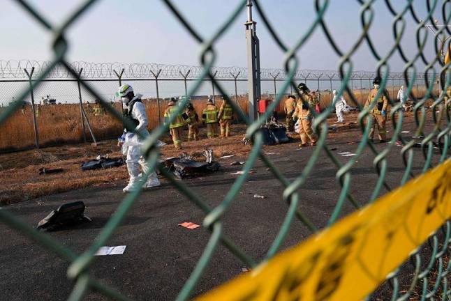 Firefighters and rescue personnel work near the scene where a Jeju Air Boeing 737-800 series aircraft crashed and burst into flames at Muan International Airport in South Jeolla Province, some 288 kilometres southwest of Seoul on December 29, 2024. A Jeju Air plane carrying 181 people from Bangkok to South Korea crashed on arrival December 29, colliding with a barrier and bursting into flames, with only two survivors rescued so far and 120 confirmed dead. - JUNG YEON-JE / AFP