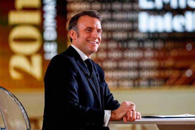 French President Emmanuel Macron smiles during a televised interview broadcasted on TV channel France 2 and in India on the eve of the Artificial Intelligence (AI) Action Summit, at the Grand Palais, in Paris, on February 9, 2025. - Gonzalo Fuentes / POOL / AFP