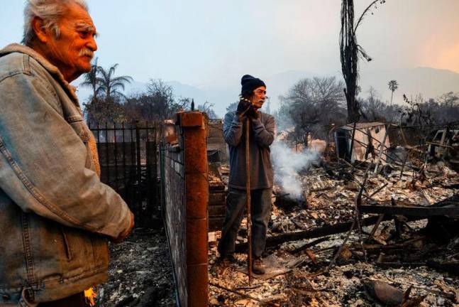 Richard Castaneda (L) and Rupert Garcia look at the ruins of Garcia’s home destroyed by the Eaton Fire in Altadena, California, on January 9, 2025. Both Garcia and Castañeda lost their homes in the Eaton Fire.