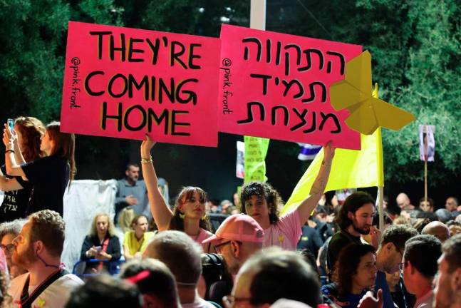 Women display placards during a gathering at Hostages Square in Tel Aviv on October 11, 2025. - AFP