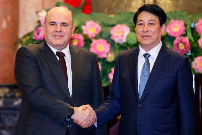 Vietnam’s President Luong Cuong (R) and Russia’s Prime Minister Mikhail Mishustin (L) shake hands during a meeting at the Presidential Palace in Hanoi on January 15, 2025. - LUONG THAI LINH / POOL / AFP