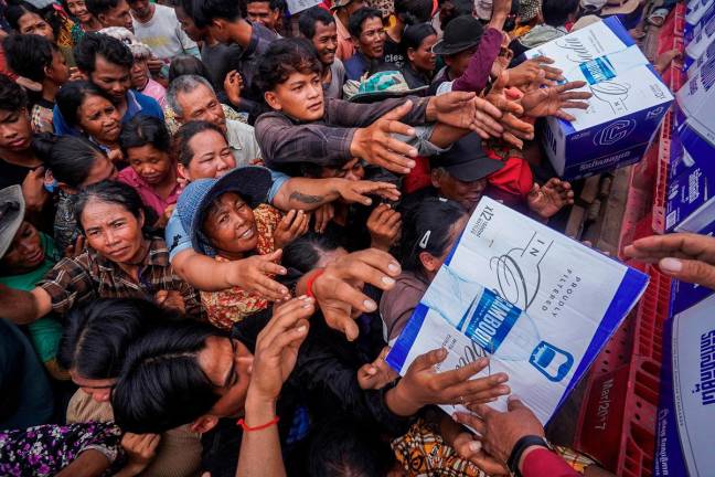 People gather to receive water supplies donated at Batthkao Primary School camp, amid ongoing clashes on the Thai-Cambodian border that extended to the third day, in Oddar Meanchey province, Cambodia, July 26, 2025. - REUTERS