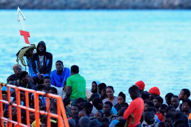 Several migrants wait to disembark from a wooden boat in the port of Arguineguin, on the island of Gran Canaria, Spain, October 20, 2024. - REUTERS/Borja Suarez