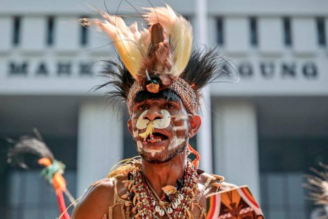 Representatives of the Awyu and Moi indigenous tribes dance and perform rituals in front of the Supreme Court building in Jakarta on May 27, 2024, during a protest, together with environmental activists, as they called on the Supreme Court to revoke the permits of palm oil companies that are set to operate on Papuan land, which could potentially clear approximately 300 square kilometers of customary forest. - BAY ISMOYO / AFP