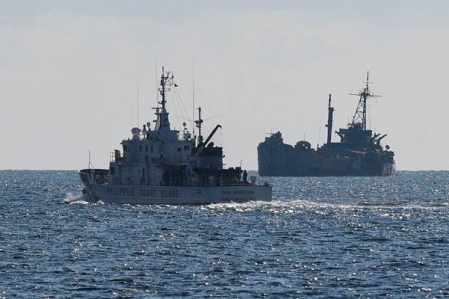 This file photo taken on April 23, 2023 shows Philippine coast guard vessel BRP Malapascua (L) patrolling near the grounded navy ship BRP Sierra Madre where Philippine marines are stationed to assert Manila’s territorial claims at Second Thomas Shoal in the Spratly Islands in the disputed South China Sea. The Philippines and China have agreed on an “arrangement” for resupplying Filipino troops stationed on a South China Sea reef, Manila said on July 21, 2024, after a series of escalatating confrontations in the disputed waters. - AFPpix