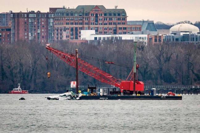 A crane moves in to place on the Potomac River for recovery efforts after the American Airlines crash on February 02, 2025 in Washington, DC. An American Airlines flight from Wichita, Kansas collided midair with a military Black Hawk helicopter while on approach to Ronald Reagan Washington National Airport on January 29, 2025 outside of Washington, DC. According to reports, there were no survivors among the 67 people onboard both aircraft. - Samuel Corum/Getty Images/AFP