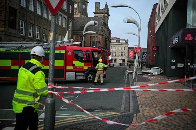 Firefighters close a street due to roof debris falling from council building in Blackpool, north-west England on January 24, 2025, as storm Eowyn brings winds of 100 mph to the UK and Ireland. A rare red warning for wind, which warns of very dangerous conditions and gusts of up to 100mph, was issued by the Met Office for Northern Ireland and Scotland on Friday. - Oli SCARFF / AFP