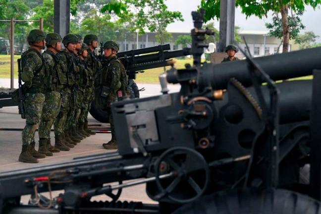 Taiwanese soldiers stand in formation beside US-made M101 howitzers during a visit by Taiwan's President Lai Ching-te at the air force base in Hualien on May 28, 2024. - Sam Yeh / AFP