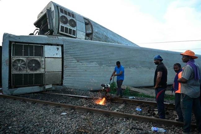 India railway workers restore the site following derailing of several coaches of the Mysuru-Darbhanga Bagmati Express train after collision with a goods train at the Kavaraipettai Railway Station, located near Gummidipundi, some 40km north of Chennai on October 12, 2024. - R. Satish BABU / AFP