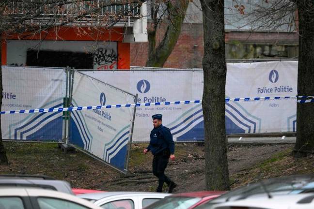 A police officers walks near a behind a police fence blocking off an investigation area at the Cite du Peterbos neighbourhood, where a man was killed overnight in a new shooting linked to drug trafficking in the municipality of Anderlecht, Brussels, on February 7, 2025. It is the third shooting since the morning of February 5 in Anderlecht, which has several known drug sales points - trafficking hotspots identified by the authorities. - NICOLAS TUCAT / AFP