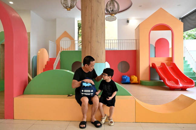 A grandfather talks to his grandchild inside a kindergarten in Hanoi on June 4, 2025. - AFPpix