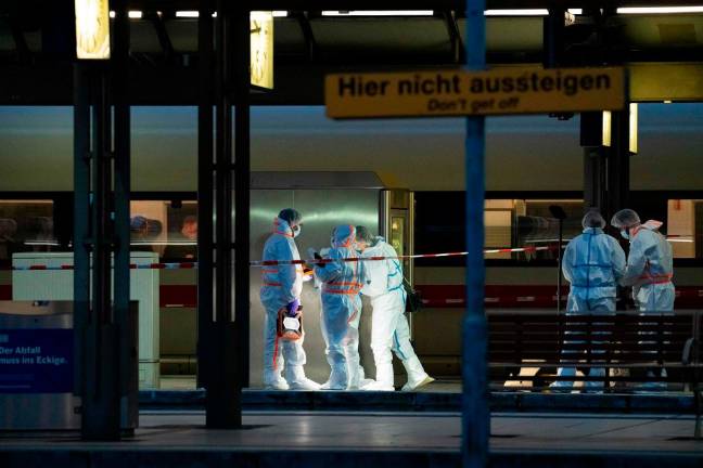 Forensic police officers investigate on the railway platform at Hamburg's main train station where at least 12 people have been injured in a knife attack on May 23, 2025. A knife attack at the main station in the German city of Hamburg left at least 12 people injured with some of them in a life-threatening condition, local emergency services said. - Jonas Walzberg / AFP