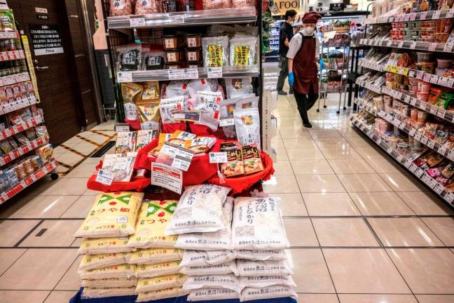 Bags of rice (C) are displayed for sale at a supermarket in Tokyo on May 23, 2025. Japan’s core inflation rate accelerated in April to 3.5 percent as rice prices almost doubled year-on-year, official data showed on May 23. - AFPpix