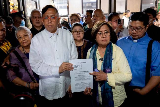 Philippine Congressman Perci Cendana and former Senator Leila de Lima, the spokesperson for an alliance of civil society groups, hold a copy of the impeachment complaint against Vice President Sara Duterte, filed by former government officials, civil society and religious leaders, on grounds of grave misconduct and constitutional violations, at the House of Representatives in Quezon City, Philippines, December 2, 2024. - REUTERS/Eloisa Lopez