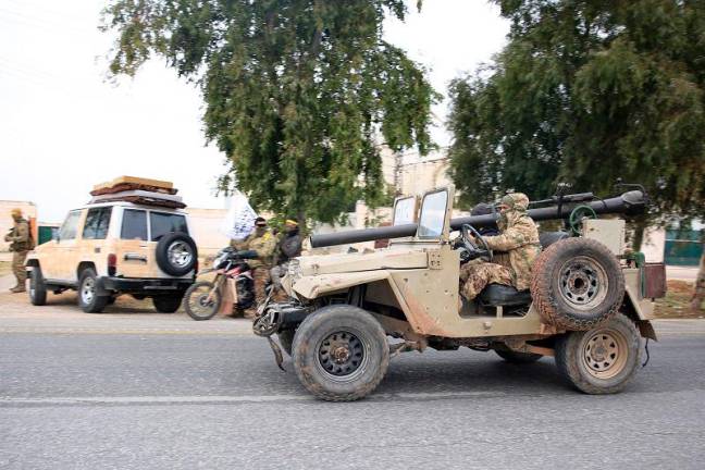 Anti-government forces drive in city of al-Rastan in Syria's west-central province of Homs on December 7, 2024, on their way to Homs. - Aref TAMMAWI / AFP