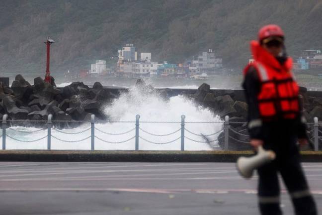 A coast guard stands on duty while waves crash against a break wall as Super Typhoon Kong-rey moves towards Taiwan, in Keelung on October 31, 2024. - I-Hwa CHENG / AFP