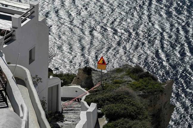 This photograph shows caution tapes placed to restrict access for tourists as a precaution due to recent seismic activities in Oia village on the Greek island of Santorini on February 5, 2025. Some 7,000 people have left the island, known for its spectacular cliffside views and dormant volcano, which has been hit by hundreds of tremors since January 24, 2025, officials said. - STRINGER / AFP