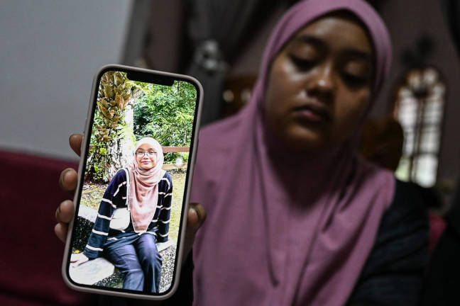The victim’s elder sister, Nur Ainul Afiqah, 22, shows a photo of her late sister, Nur Ainul Qistina, 21, who was involved in a bus accident on the East-West Highway (JRTB) near Tasik Banding, Gerik, early this morning.