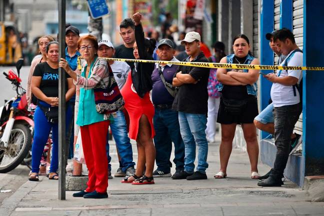 Bystanders look at the site where eight people were killed in Pascuales District, Guayaquil, Ecuador, on June 10, 2025. - MARCOS PIN / AFP