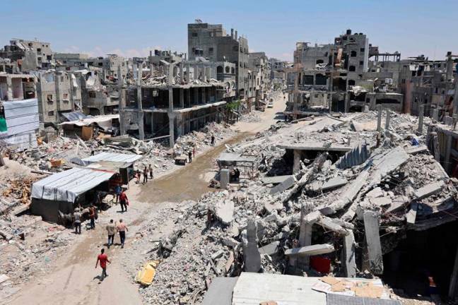 Palestinians walk past the rubble of buildings and open sewage, as garbage collection and any other municipality services come to a halt due to the Israeli bombardment of the Gaza Strip, in the Jabalia refugee camp, in the northern Gaza Strip on July 21, 2024, amid the ongoing conflict between Israel and the Palestinian Hamas militant group. - Omar AL-QATTAA / AFP