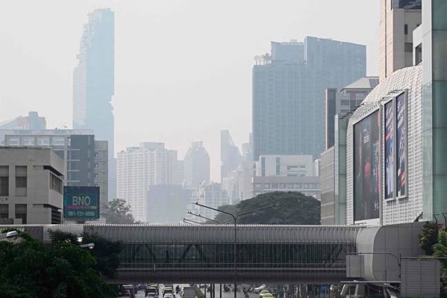 People are seen walking through a pedestrian bridge amidst high levels of air pollution in Bangkok on January 24, 2025. - Lillian SUWANRUMPHA / AFP