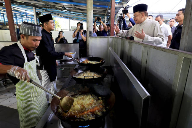Perdana Menteri Datuk Seri Anwar Ibrahim beramah mesra bersama tukang masak di Restoran Pak Zain Patin di Jalan Kampung Orang Asli Bukit Dugang untuk menikmati makan tengah hari, hari ini. - BERNAMApix