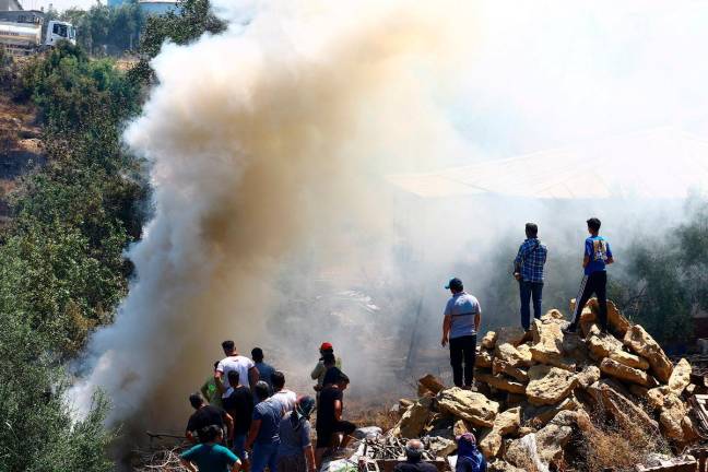People stand next to smoke rising from the wildfire in the Aksu district of Antalya, a Mediterranean city in southern Turkey, July 25, 2025. - REUTERS