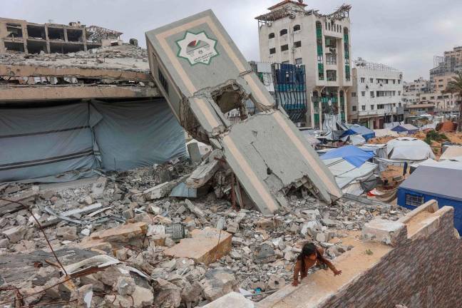 A Palestinian girl plays on the rubble of a Palestinian Authority's Legislative Council building near a makeshift displacement camp set up amid building rubble in Gaza City on May 12, 2025. Israeli Prime Minister Benjamin Netanyahu said on May 12 that the release of a US-Israeli hostage announced by Hamas would not lead to a ceasefire in the Gaza Strip or the release of Palestinian detainees. - Omar AL-QATTAA / AFP