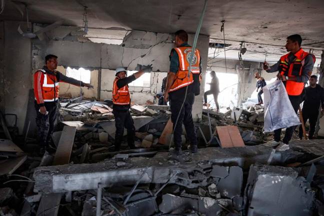 Rescuers search through the rubble in the aftermath of an Israeli strike that hit an administrative building in Khan Yunis in the southern Gaza Strip on January 2, 2025, amid the ongoing war between Israel and the Hamas movement. - BASHAR TALEB / AFP