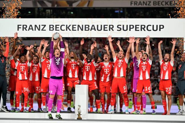 Munich’s team celebrates on the podium with the trophy after the Franz-Beckenbauer Supercup football match between VfB Stuttgart and FC Bayern Munich in Stuttgart, southern Germany. - AFP