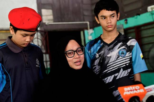 The wife of the late Corporal Amiruddin Zabri, Norazian Mohd Joned, 38, (centre), along with her sons Amirul Firdaus Amiruddin, 12, (left), and Amirul Asyraf Amiruddin, 11, was met by the media during the National Higher Education Fund Corporation (PTPTN)’s Ziarah Kasih programme in Kampung Sungai Itik today. - BERNAMApix