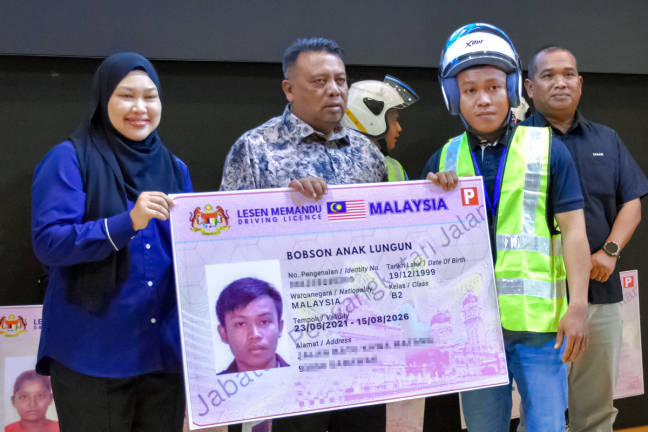State Executive Councillor for Public Works, Infrastructure, Public Facilities, and Transport, Datuk Hameed Mytheen Kunju Basheer (second from left), presented a replica driving license to Bobson Anak Lungun (right) after officiating the 2025 MyLesen (B2) License Presentation Ceremony organized by the Melaka Road Transport Department (JPJ) here today. - BERNAMA