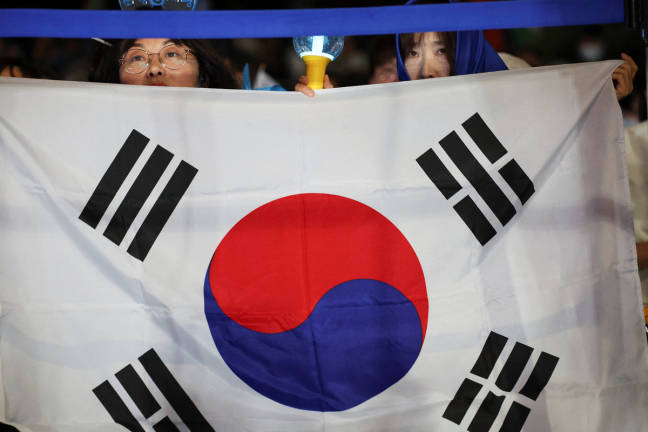 A woman holds a South Korea’s flag as supporters wait for Lee Jae-myung, the presidential candidate for South Korea’s Democratic Party, on the day of the presidential election, near the National Assembly in Seoul, South Korea, June 3, 2025. - REUTERSpix