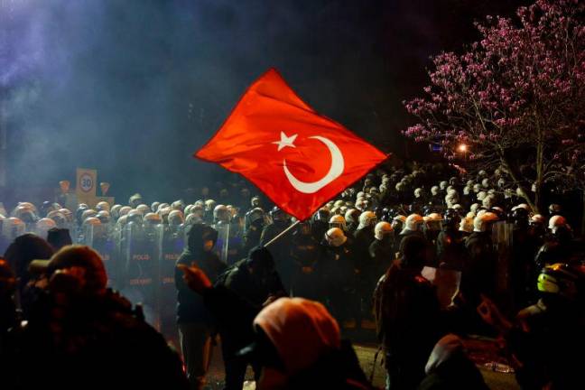 A demonstrator waves a Turkish flag next to police officers in riot gear during a protest against the detention of Istanbul Mayor Ekrem Imamoglu, in Istanbul, Turkey, March 22, 2025.REUTERSpix