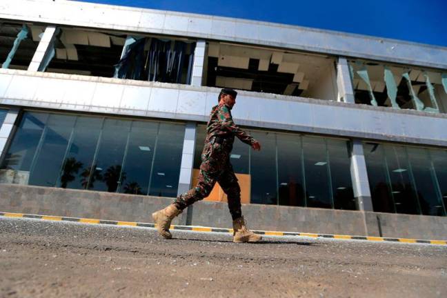 A member of Yemen's security forces walks past a damaged building at Sanaa international airport on December 27, 2024, following Israeli strikes at the site the previous day. Yemeni rebels claimed new attacks against Israel on December 27, after Israeli air strikes hit rebel-held Sanaa's international airport and other targets in Yemen. - Mohammed HUWAIS / AFP