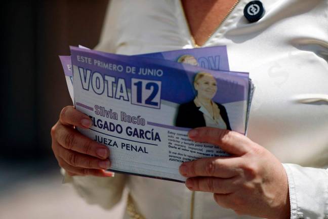 Silvia Rocio Delgado Garcia, candidate for criminal judge for the state of Chihuahua, holds campaign flyers at the Paso del Norte international bridge in Ciudad Juarez, Chihuahua State, Mexico on May 17, 2025. Delgado Garcia was part of the defense of Joaquin Guzman Loera, known as 'El Chapo,' leader of the Sinaloa cartel, while he was held at the Federal Center for Social Readaptation (Cefereso) No. 9 in Ciudad Juarez. - Herika Martinez / AFP