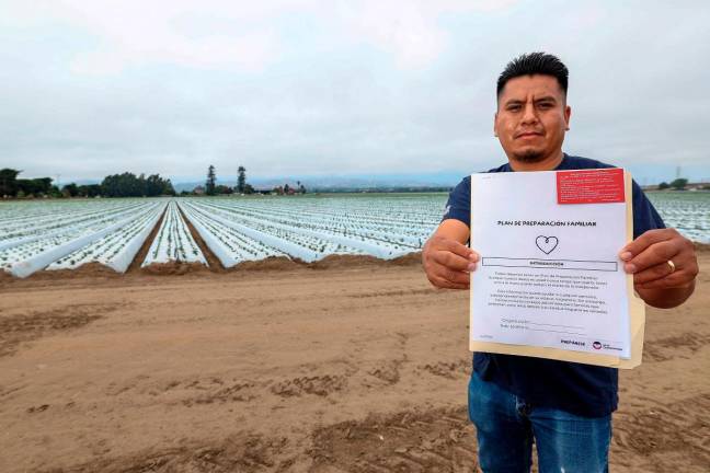 Francisco Panfilo holds a ‘plan de preparacion familiar’ (family preparedness plan) in front of a strawberry field, in Oxnard, California, on July 14, 2025. - AFP