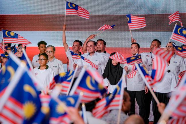 Prime Minister Datuk Seri Anwar Ibrahim hoisting the Jalur Gemilang at the National Month and Jalur Gemilang Flying 2025 launching ceremony at Dataran Tanjung Emas today. - Bernama