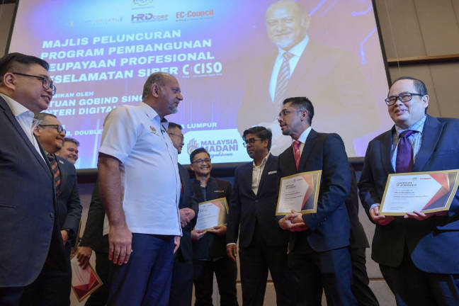 Menteri Digital Gobind Singh Deo (dua, kiri) beramah mesra bersama penerima sijil pada Majlis Peluncuran Program Pembangunan Keupayaan Profesional Keselamatan Siber di sebuah hotel hari ini. - BERNAMApix