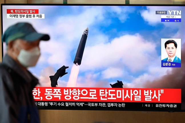 A man walks past a television screen showing a news broadcast with file footage of a North Korean missile test, at a train station in Seoul on October 22, 2025. North Korea fired at least one ballistic missile on October 22, Seoul’s military said, its first such launch in months. - AFP